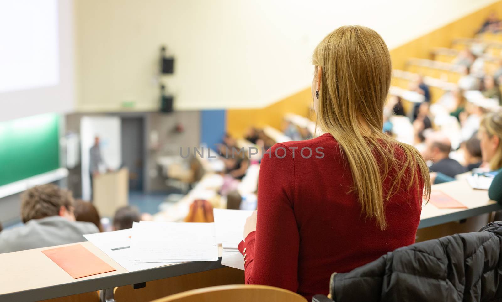 Female student attending faculty lecture workshop making notes. Audience at the lecture hall. Conference and Presentation. Business and entrepreneurship academic education concept.