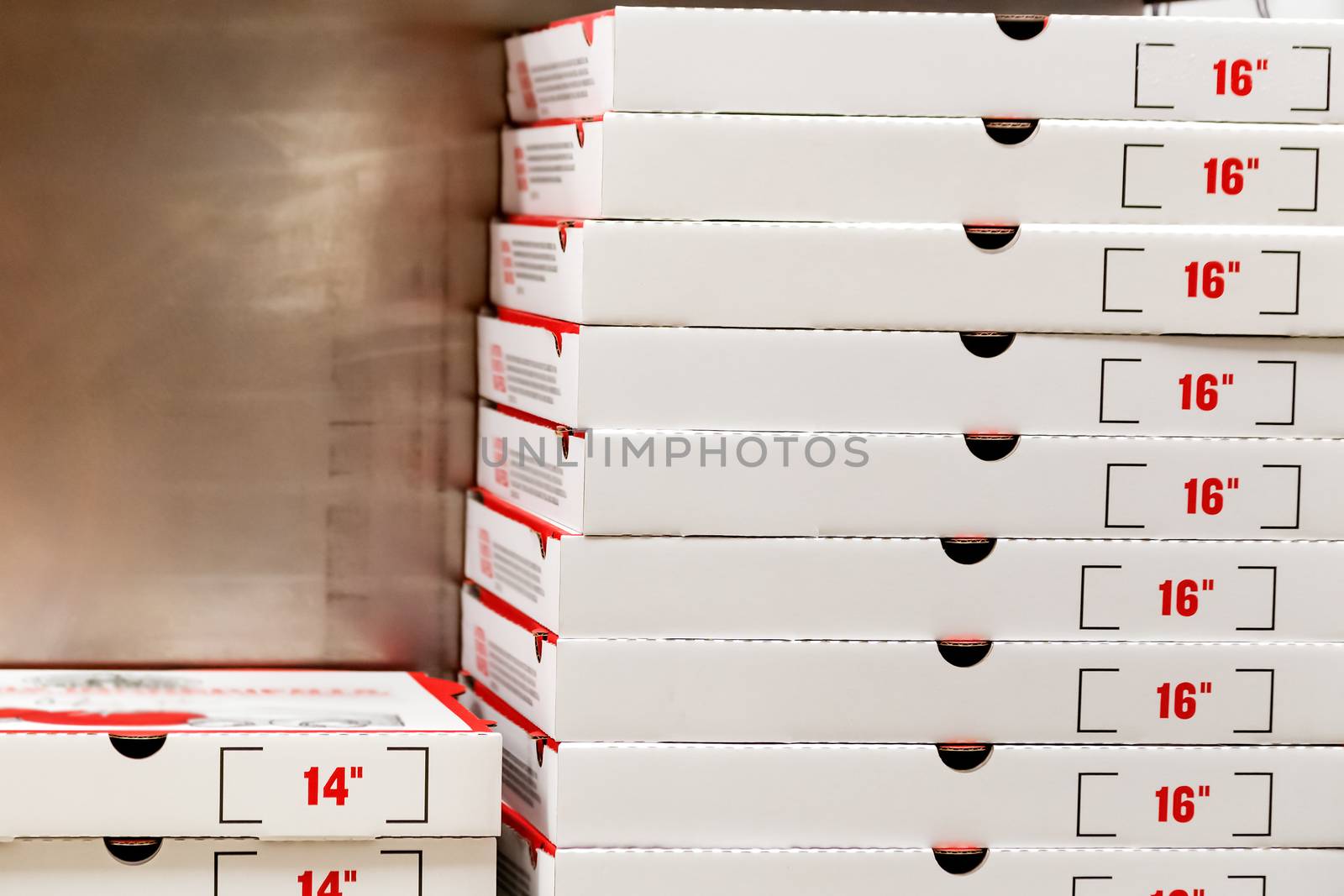 A large stack of white pizza boxes with red numbers diaimeter 16