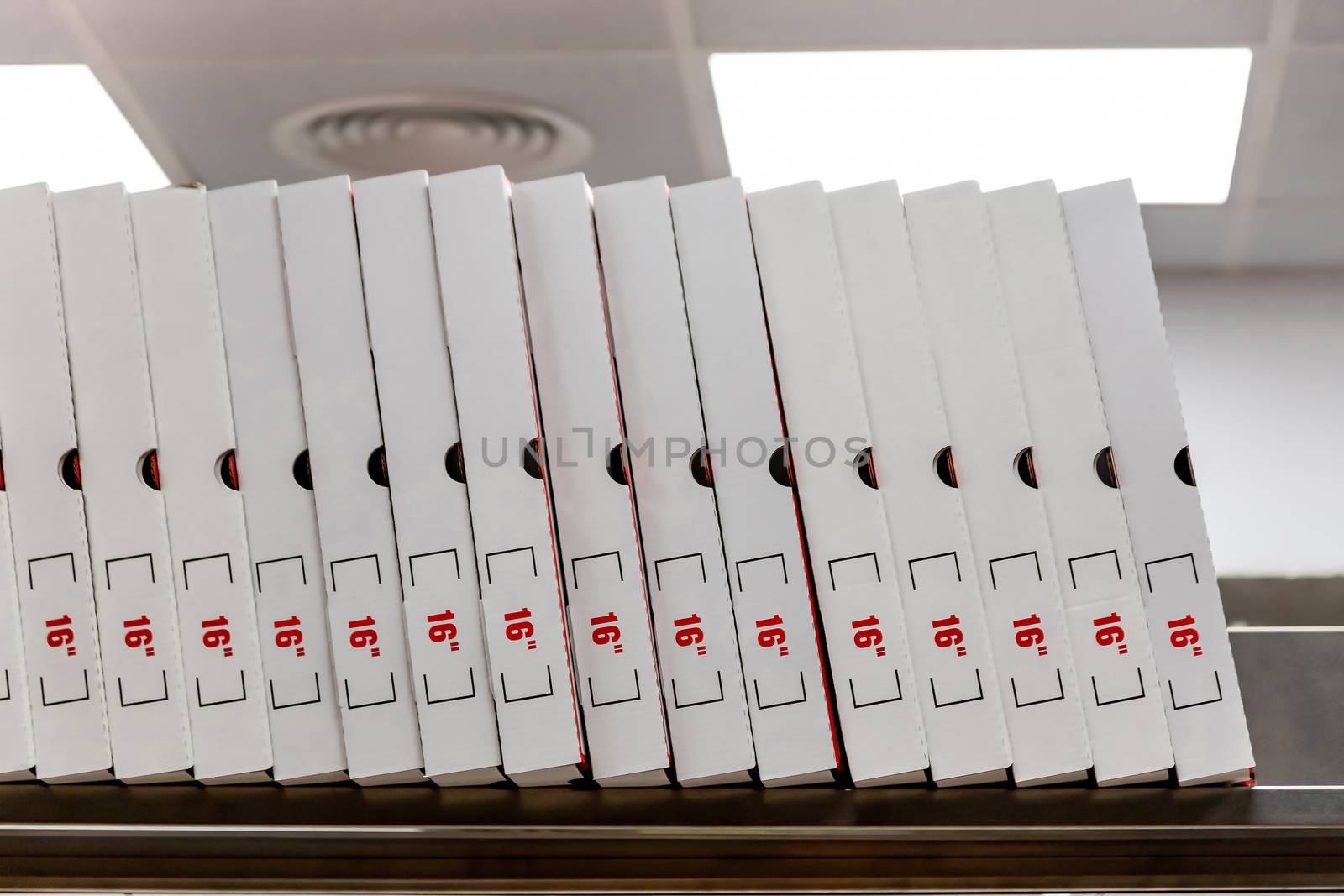 A large stack of white pizza boxes with red numbers diaimeter 16