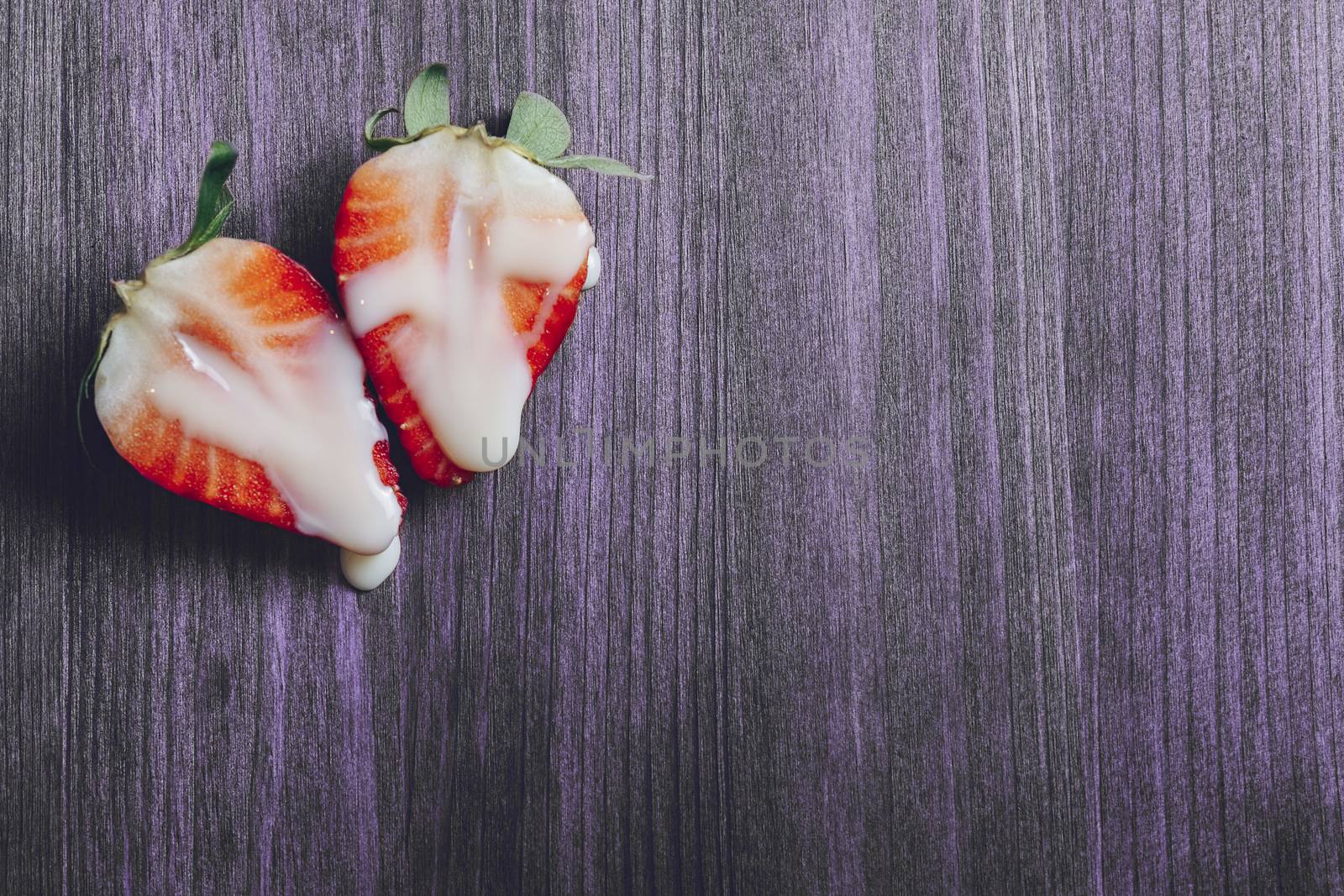 metaphor of sex with strawberries and milk on a purple wooden table. Vagina and semen symbol, sex concept. Top view, copy space for text