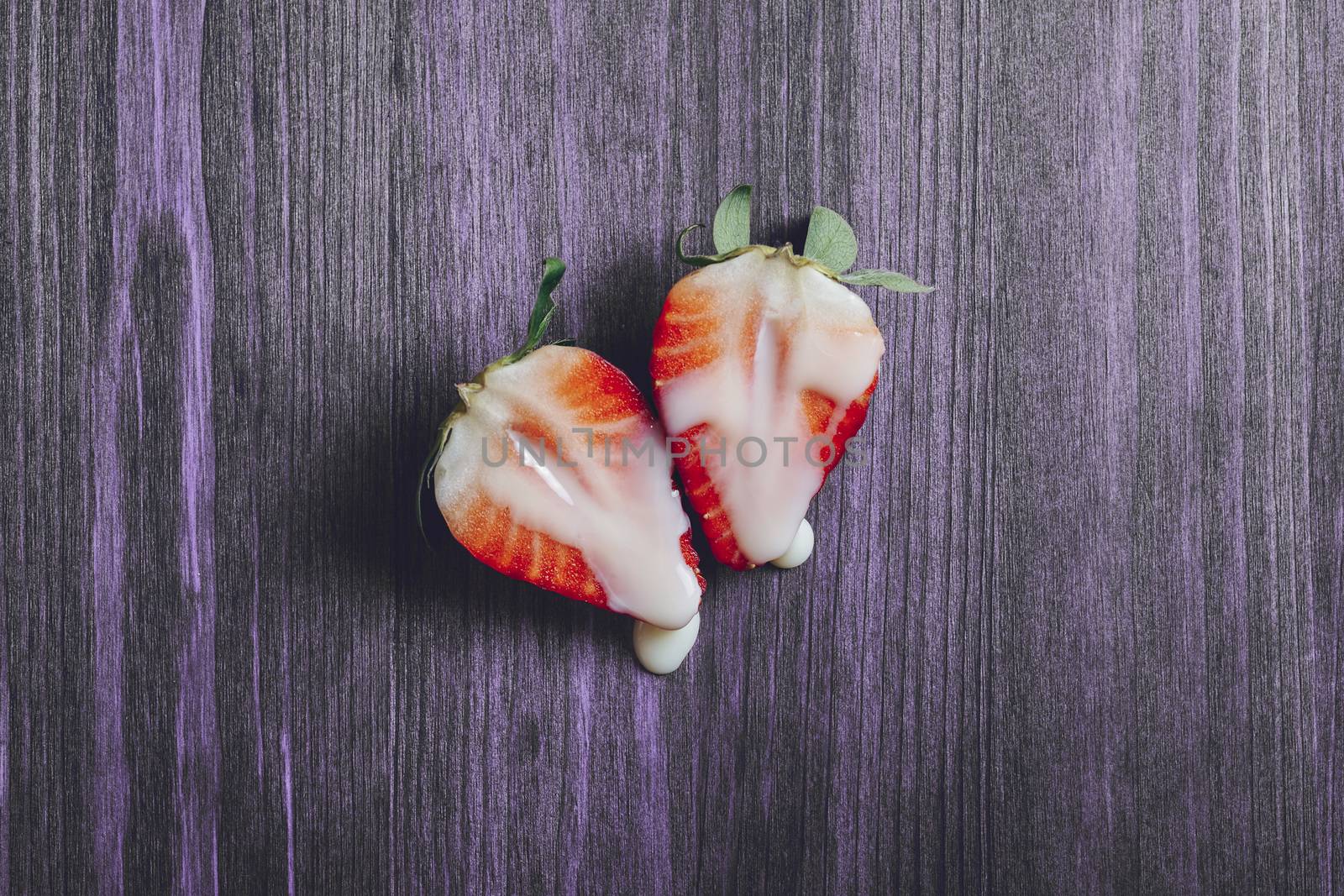 metaphor of sex with strawberries and milk on a purple wooden background. Vagina and semen symbol, sex concept. Top view, copy space for text