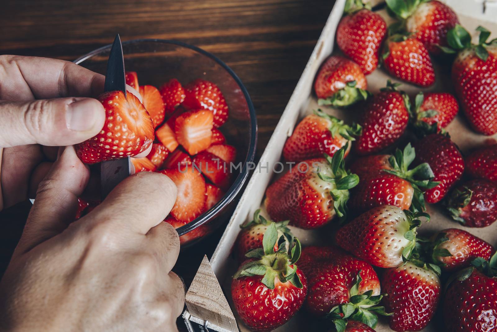 chef hand and knife slicing fresh strawberry on wooden cutting table, healthy sweet food, vitamins and fruity concept