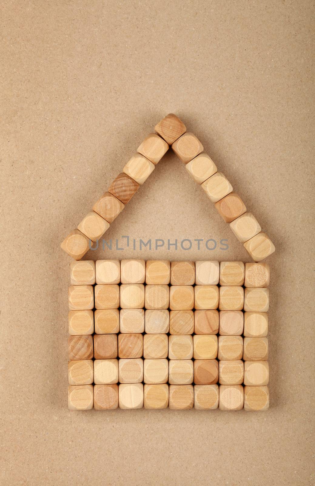 Close up wooden toy building blocks in shape of house over brown paper parchment  background copy space