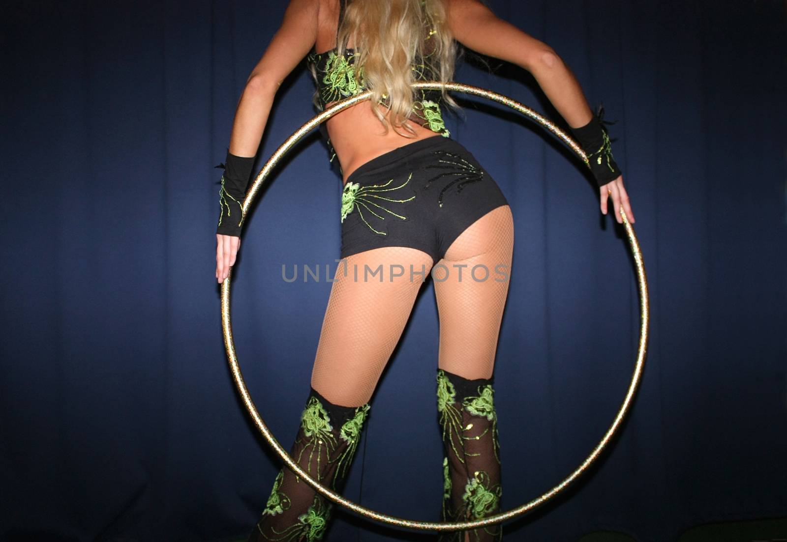 the girl stands with her back and holds the hula hoop with her hands behind her back.