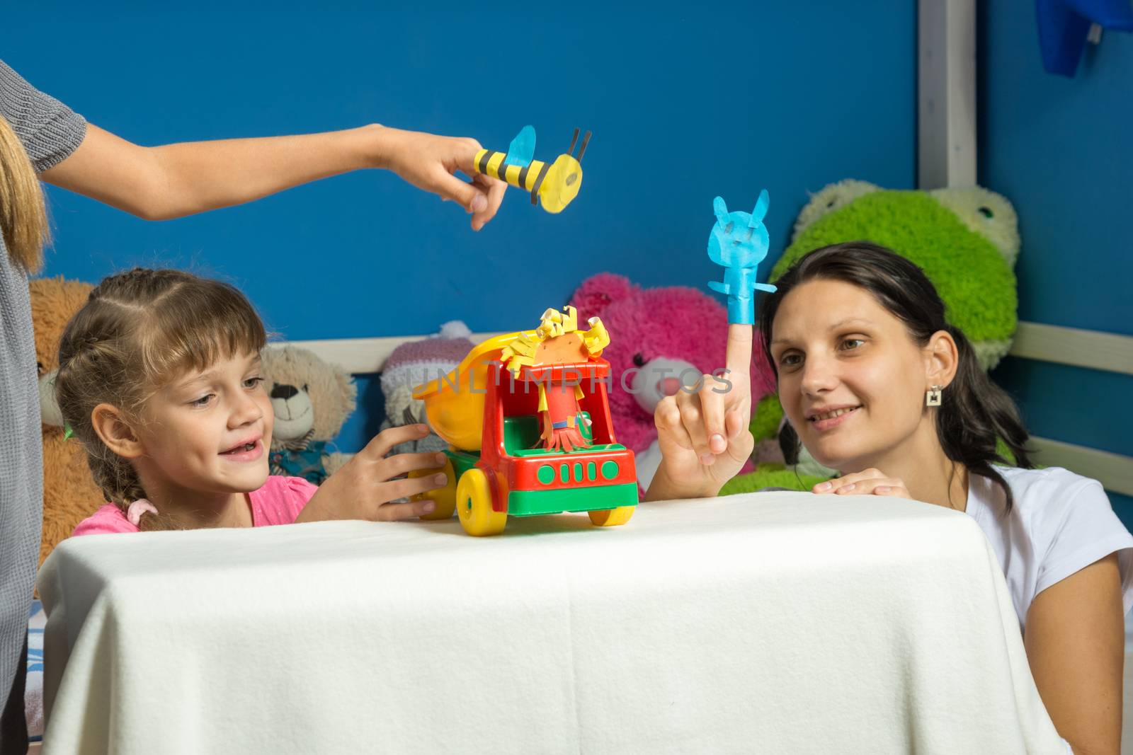 An enthusiastic mother plays with daughters in a self-made finger puppet theater by Madhourse