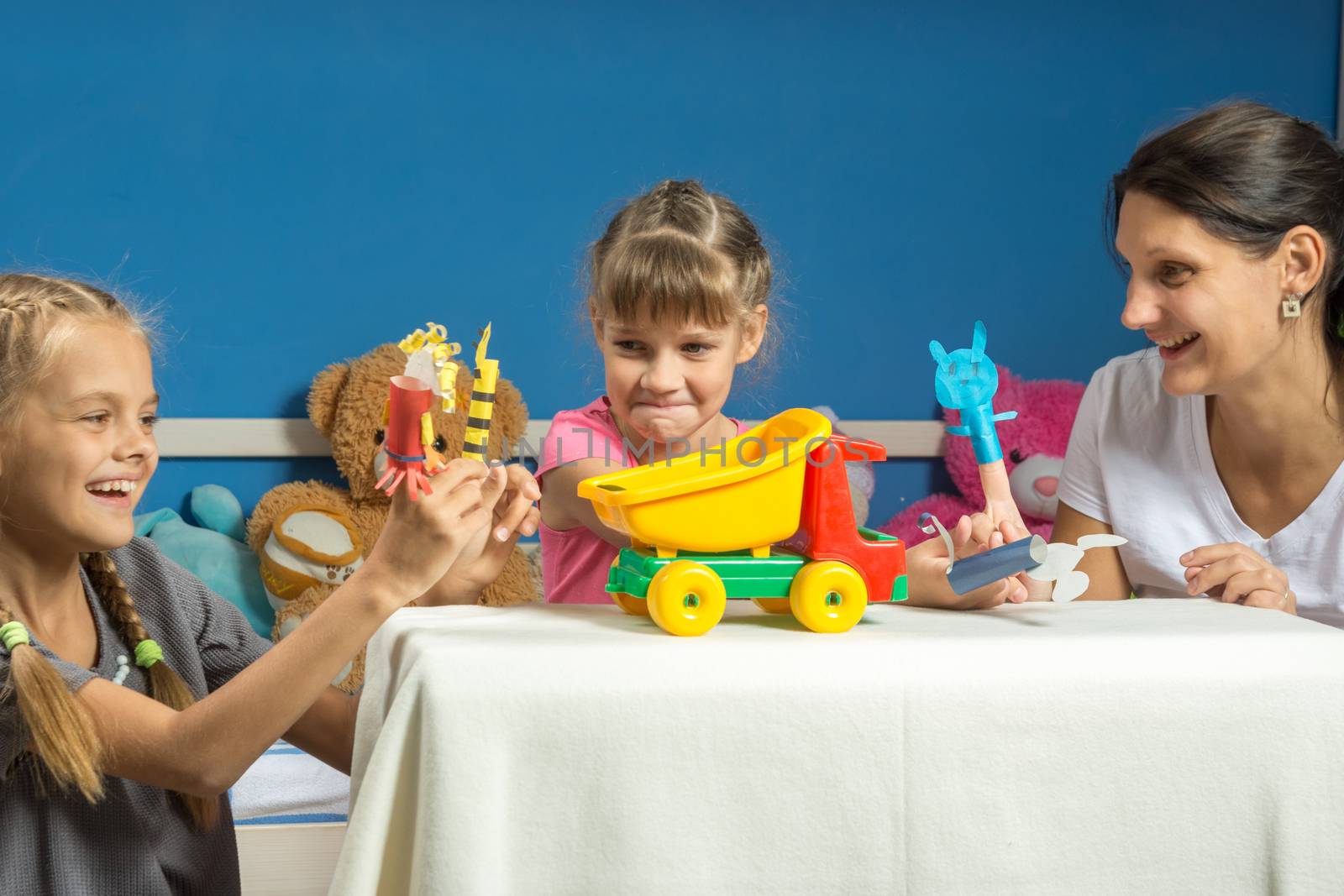 Mom plays with two daughters in a self-made finger puppet theater