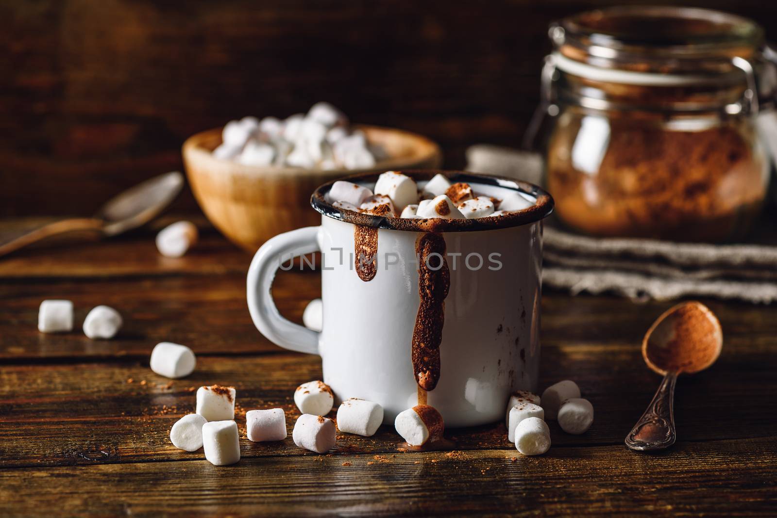 Cocoa Mug with Marshmallows. Jar of Cocoa Powder and Marshmallow Bowl on Backdrop.