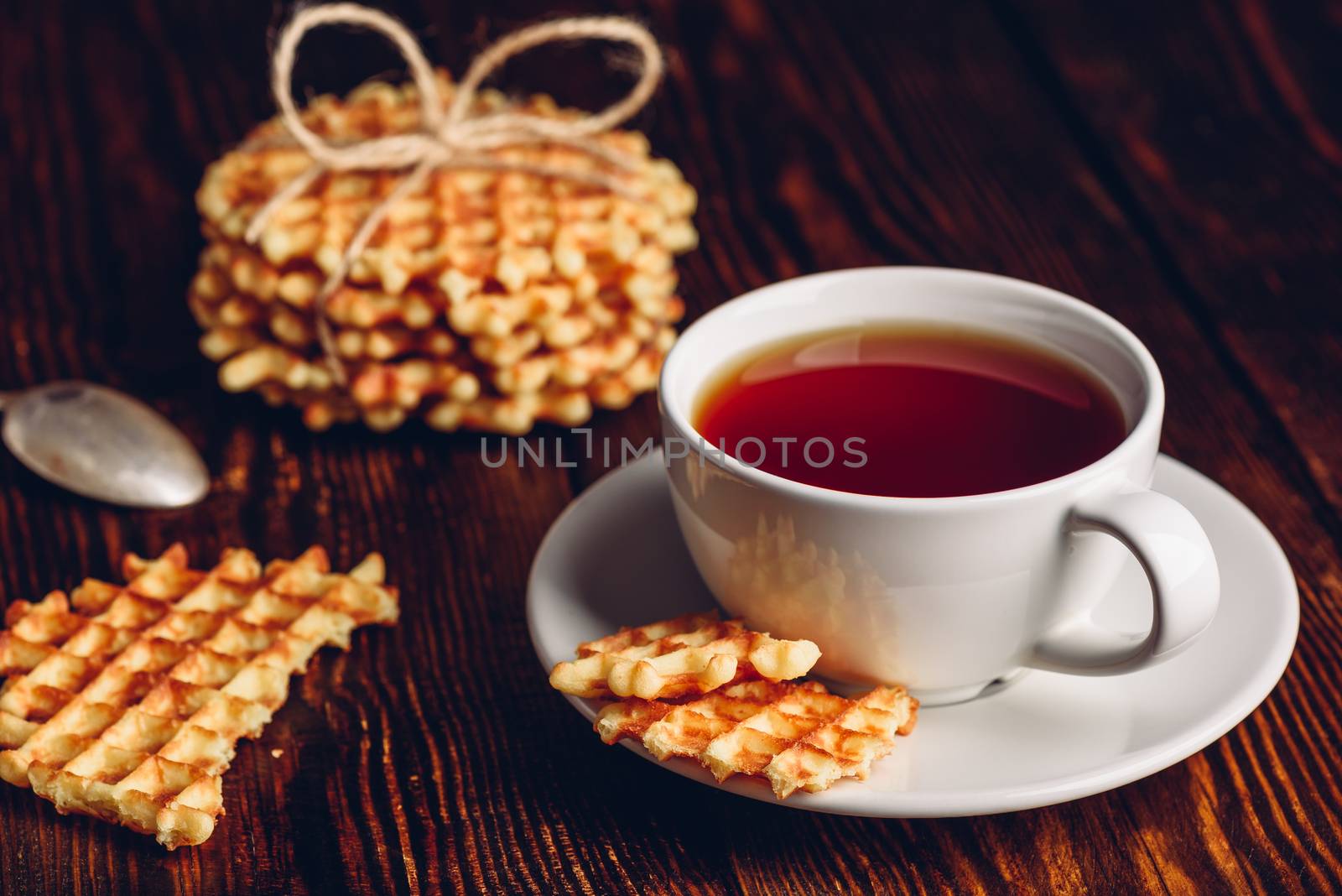 White Cup of Tea with Belgian Waffles Stack and Pieces of Waffle on Wooden Surface.