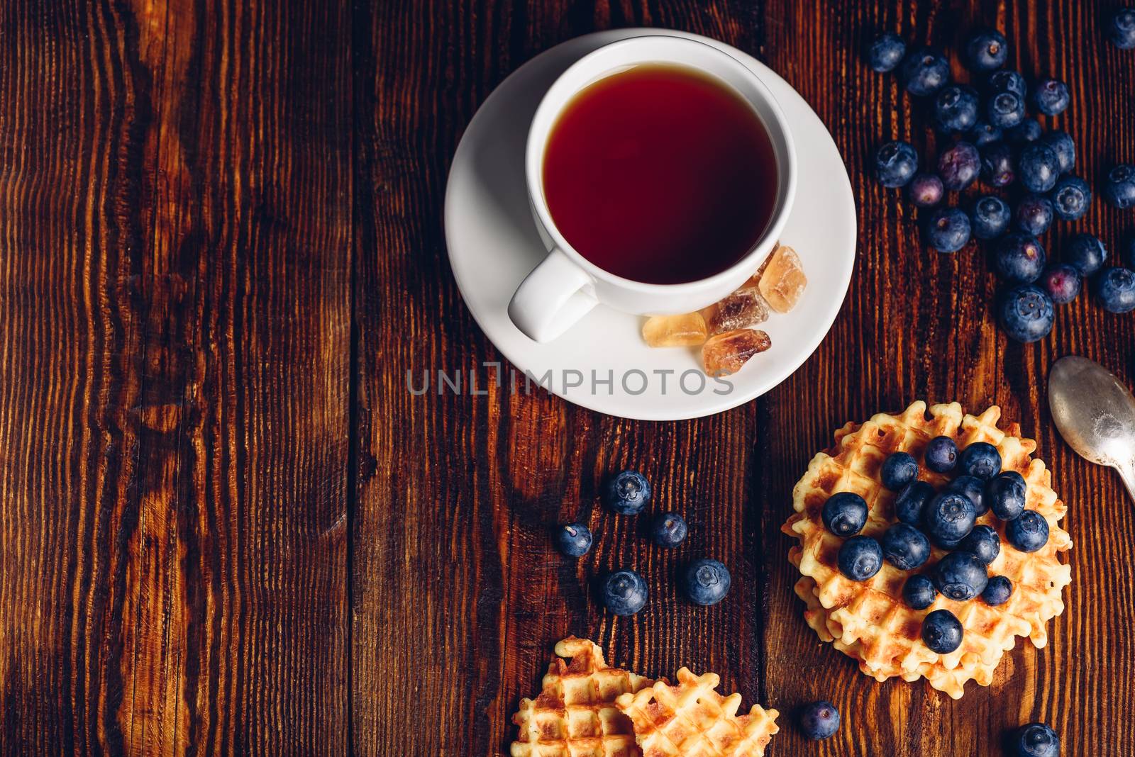White Cup of Tea with Blueberry and Homemade Waffles on Wooden Background. Copy Space on the Left.