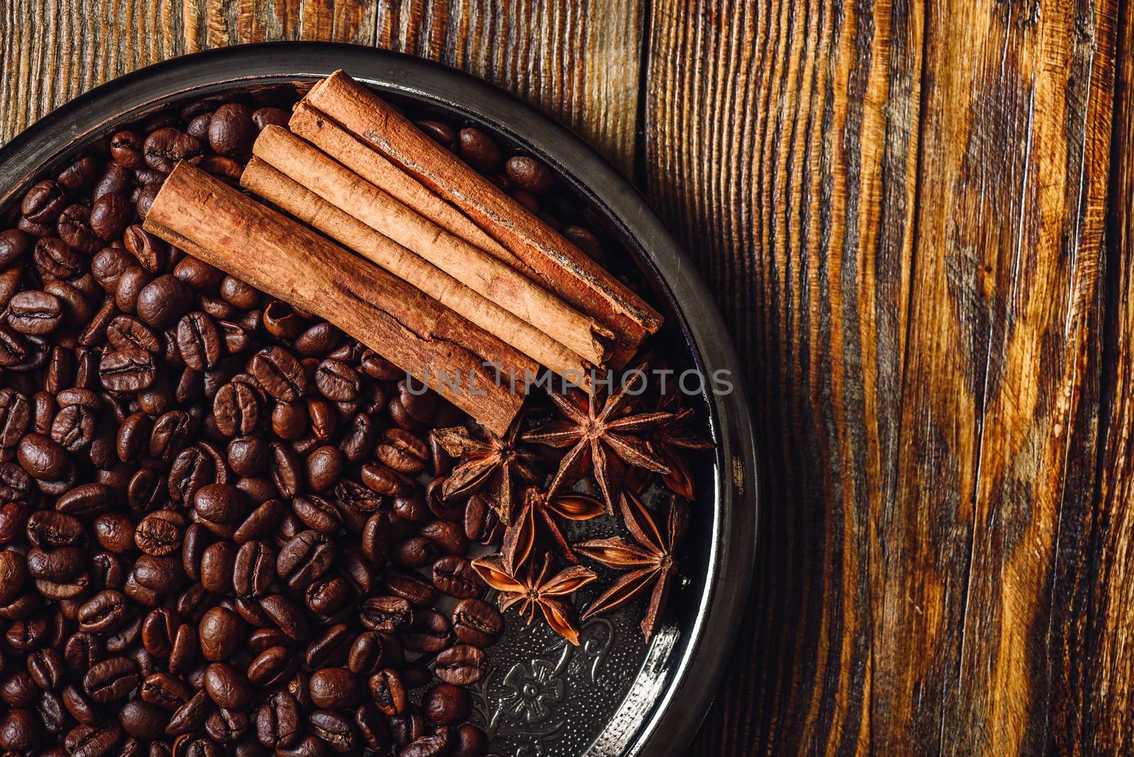 Coffee Beans with Cinnamon Sticks and Chinese Star Anise on Metal Plate. View from Above. Copy Space on the Right SIde.