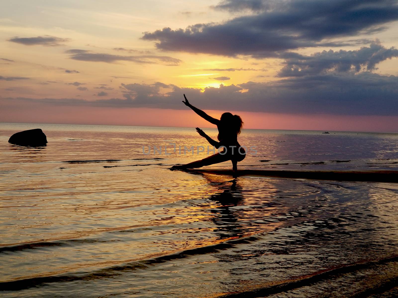 silhouette of a girl practicing yoga on the beach. Shooting against the sun. Sunset over the sea by zakob337