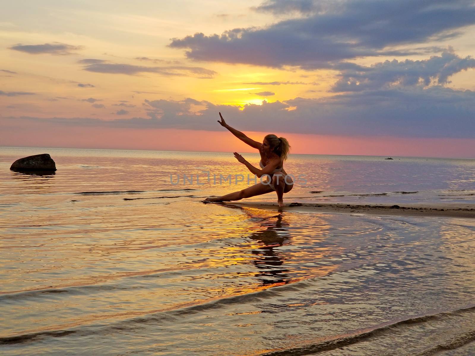 silhouette of a girl practicing yoga on the beach. Shooting against the sun. Sunset over the sea.