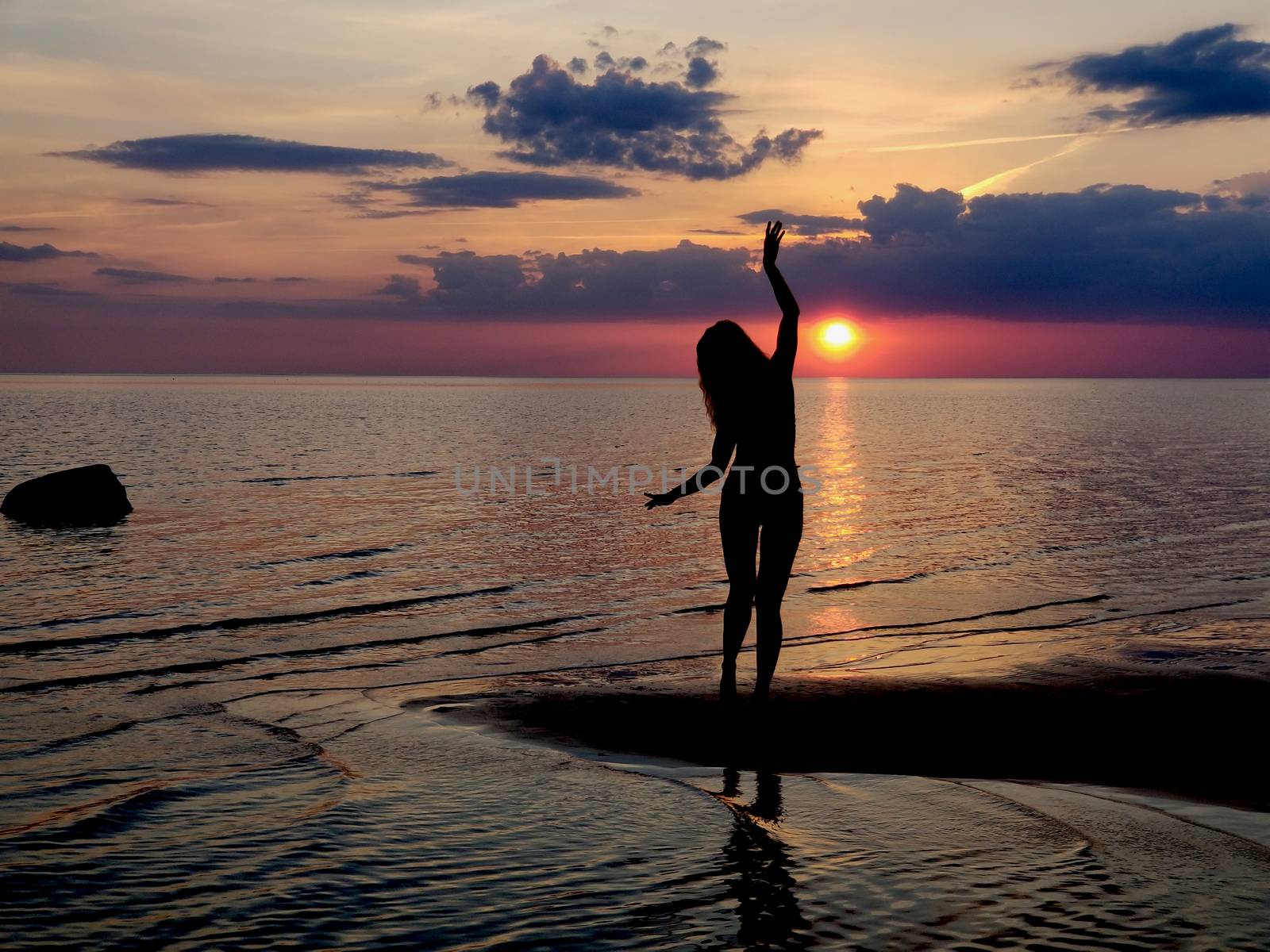 silhouette of a girl posing yoga on the beach. Shooting against the sun. Sunset over the sea