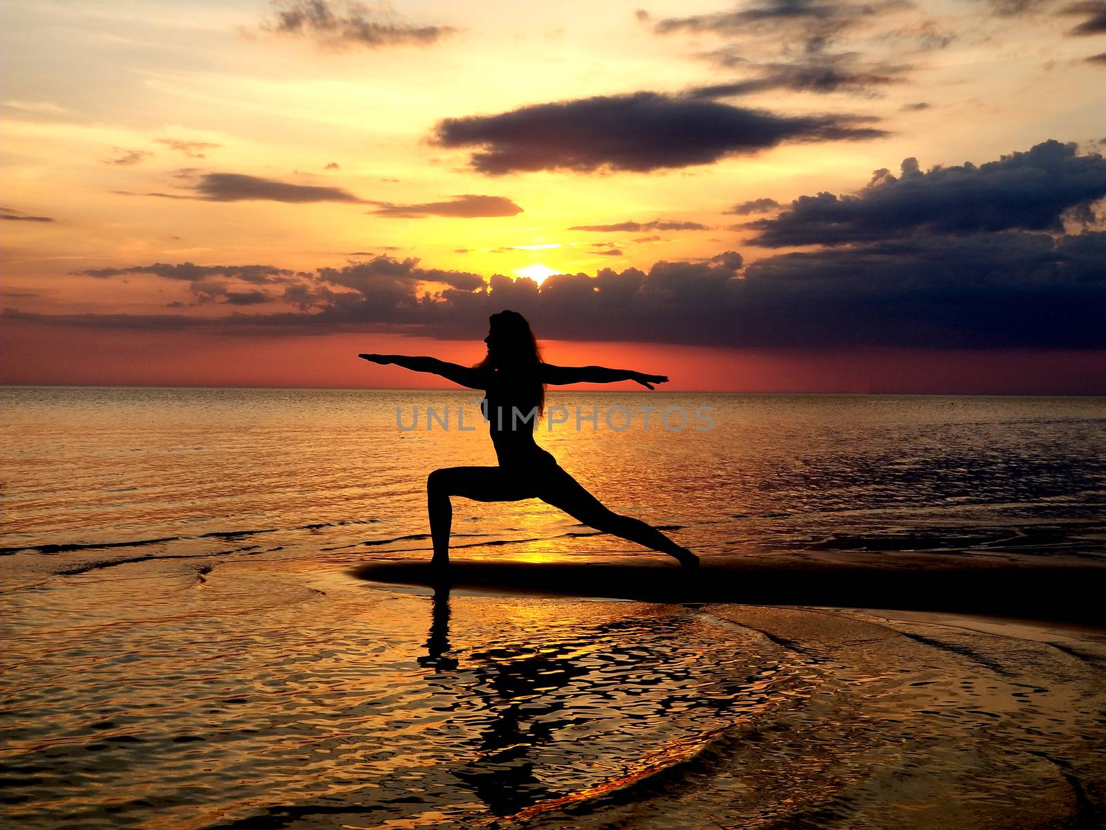 silhouette of a girl practicing yoga on the beach. Shooting against the sun. Sunset over the sea by zakob337