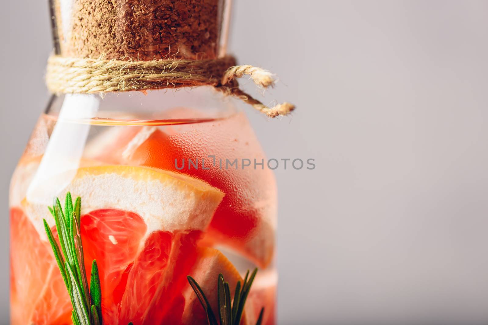 Part of Bottle with Grapefruit and Rosemary infused Water. Close up. Copy Space on the Right.