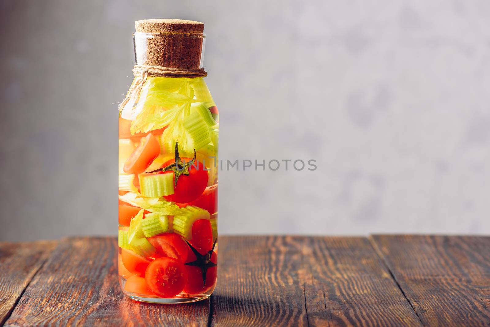 Bottle of Water Infused with Cherry Tomato and Celery Stems. Copy Space on the Right.