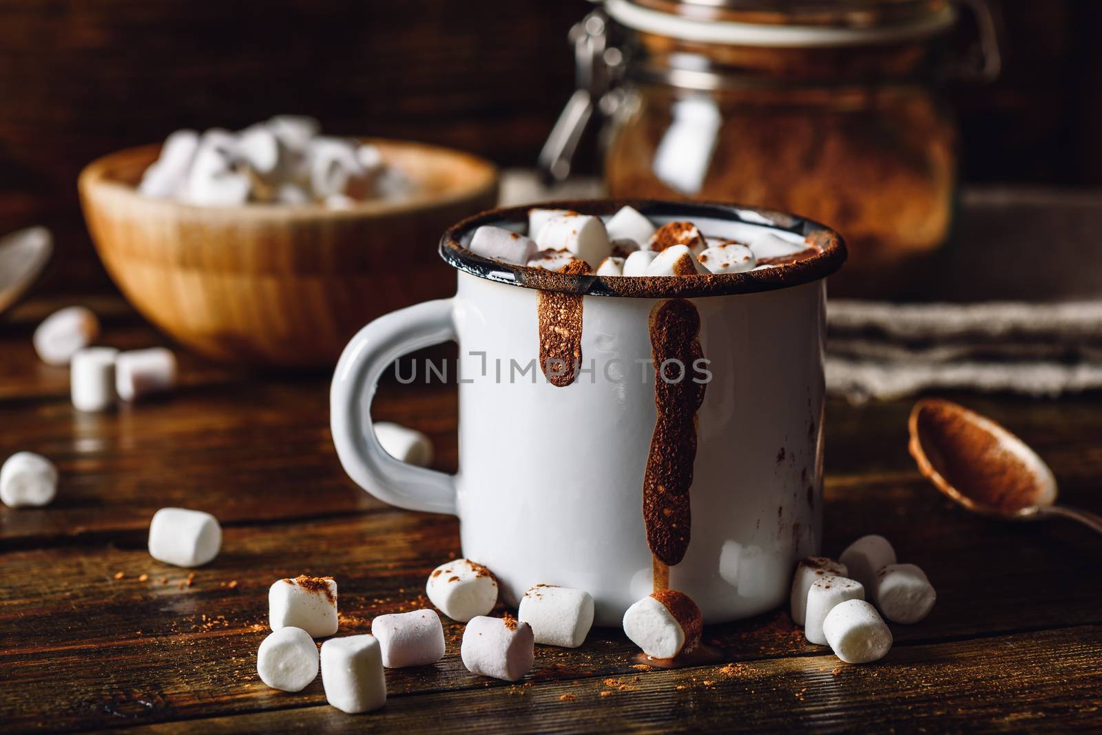 Homemade Cocoa Mug with Marshmallows. Jar of Cocoa Powder and Marshmallow Bowl on Backdrop.