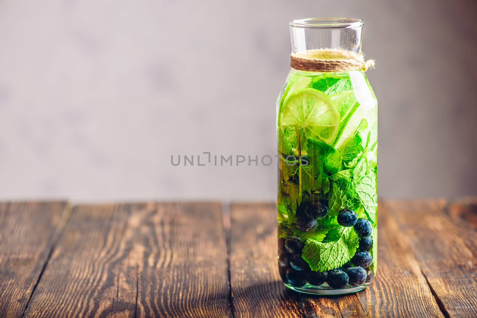Bottle of Infused Water with Lime, Mint and Blueberry. Copy Space on the Left.