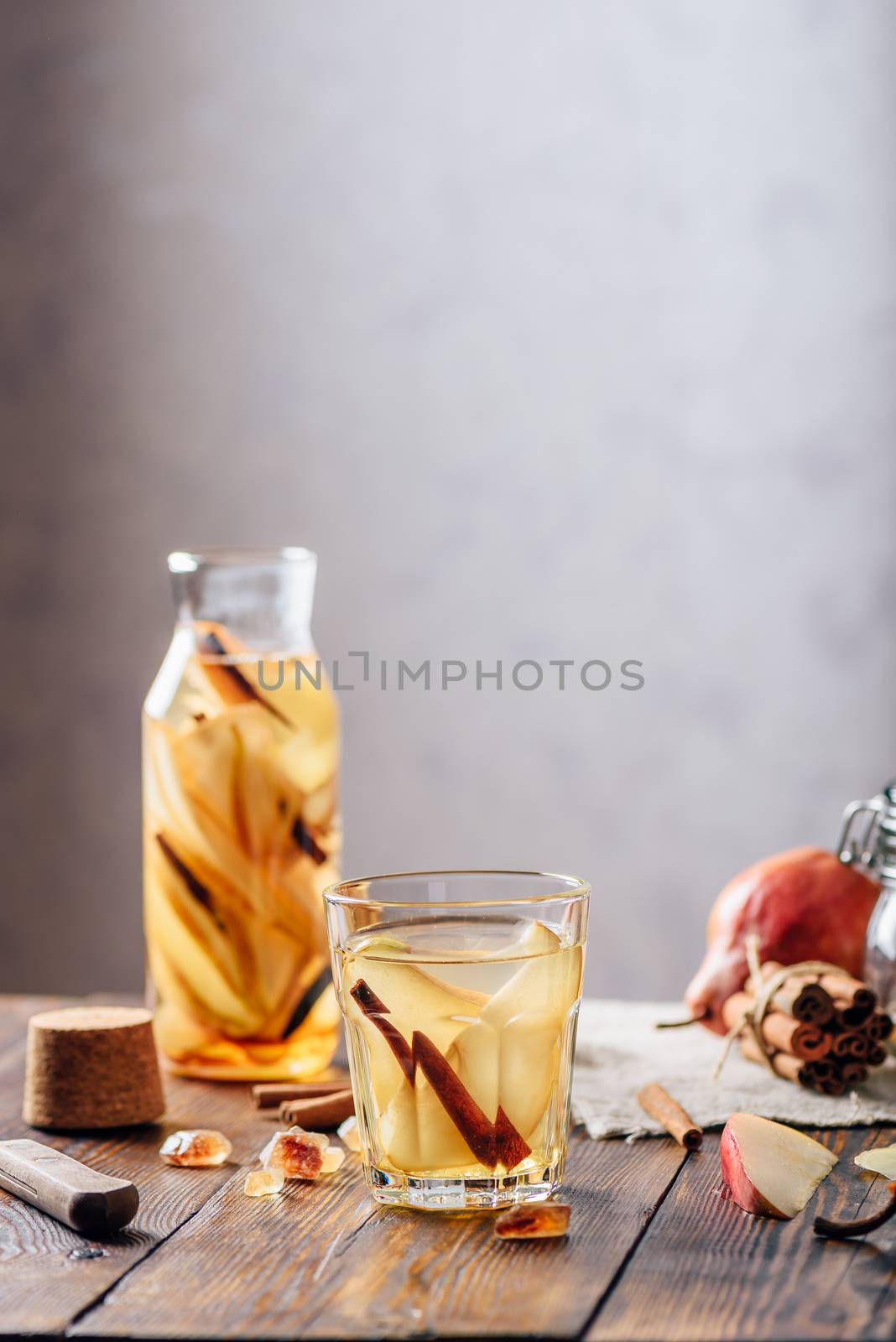 Flavored Water in Glass and Bottle with Sliced Pear, Cinnamon Stick, Ginger Root and Some Sugar. Ingredients on Wooden Table. Vertical Orientation.