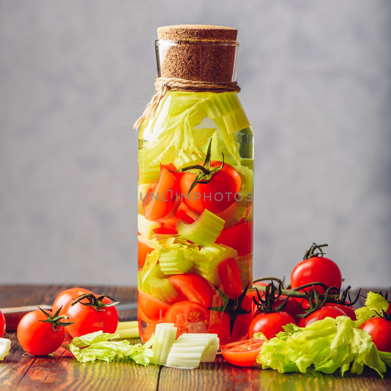 Cleansing Water Infused with Celery Stems and Cherry Tomatoes. Ingredients Scattered on Wooden Table.