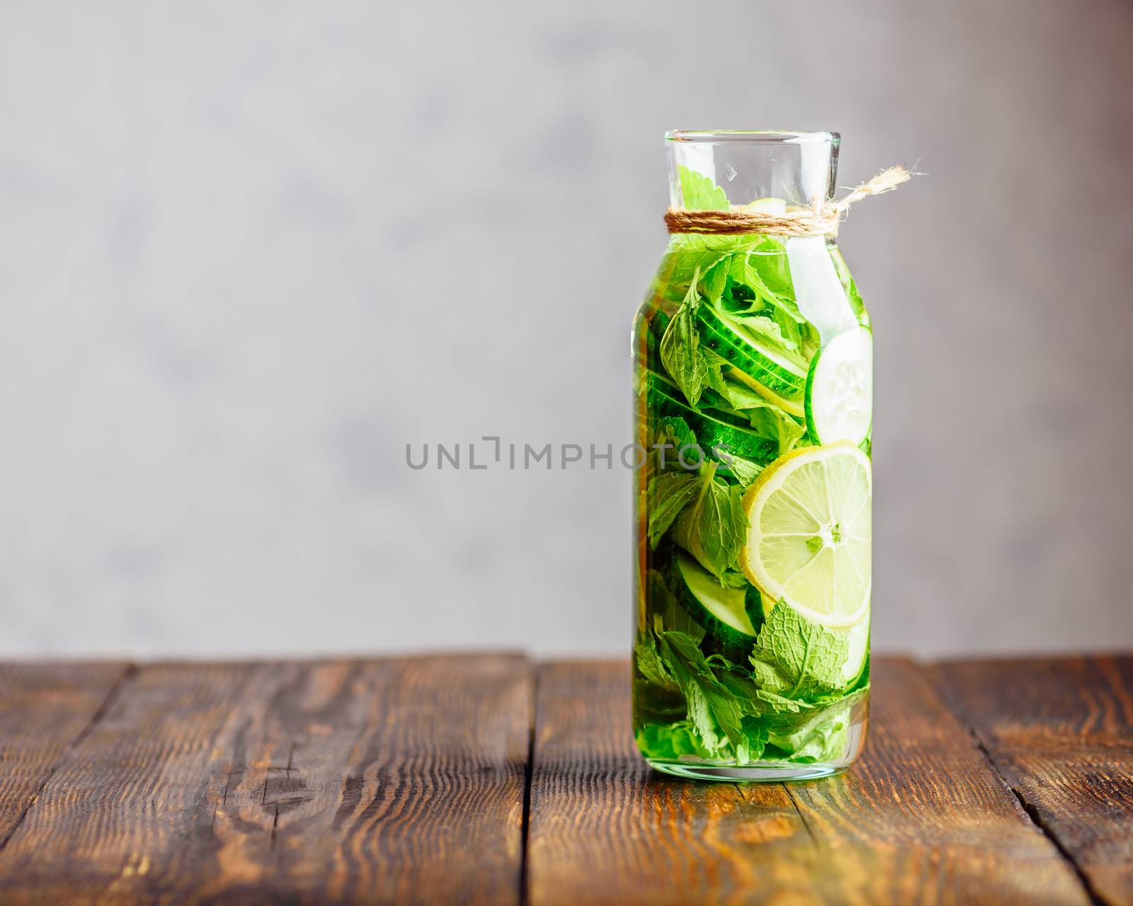 Detox Water Infused with Sliced Lemon, Cucumber and Fresh Sprigs of Mint. Copy Space on the Left.