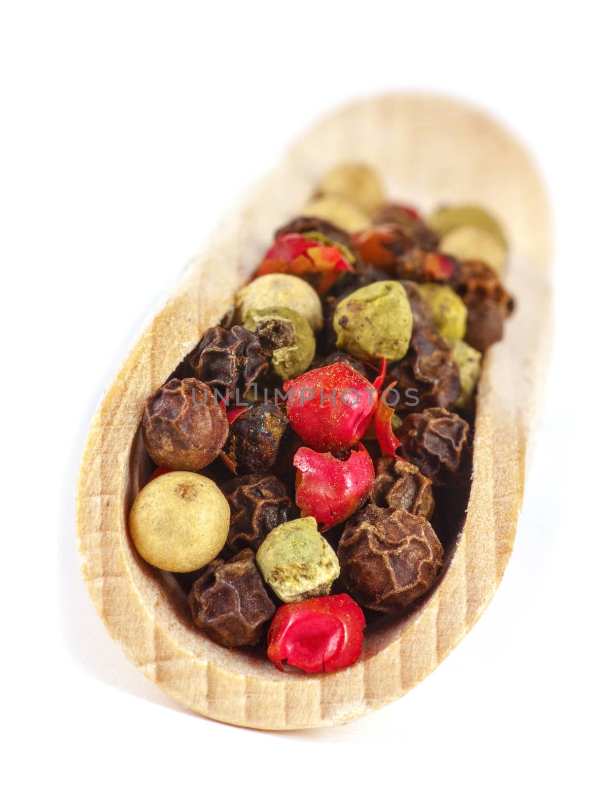 Dried seeds of color pepper on wooden spatula. Soft focus. Isolated on white background.