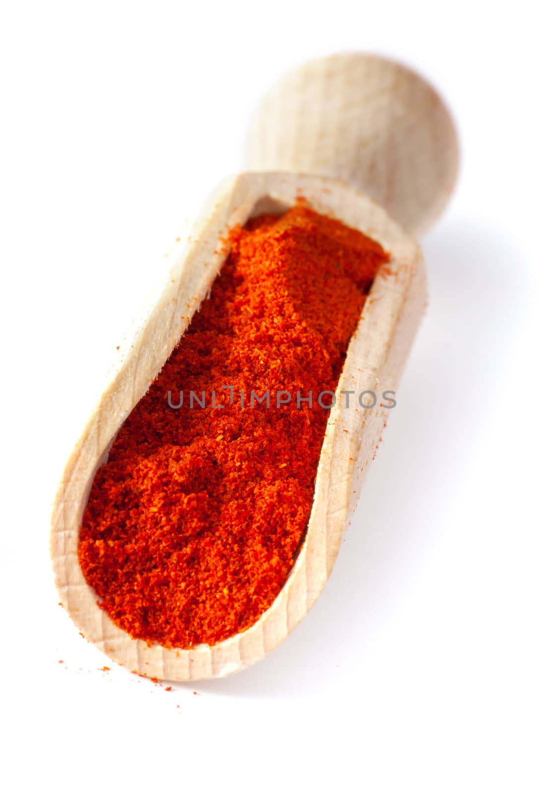 Red pepper ground. Spice powder on wooden spoon, isolated over White Background.