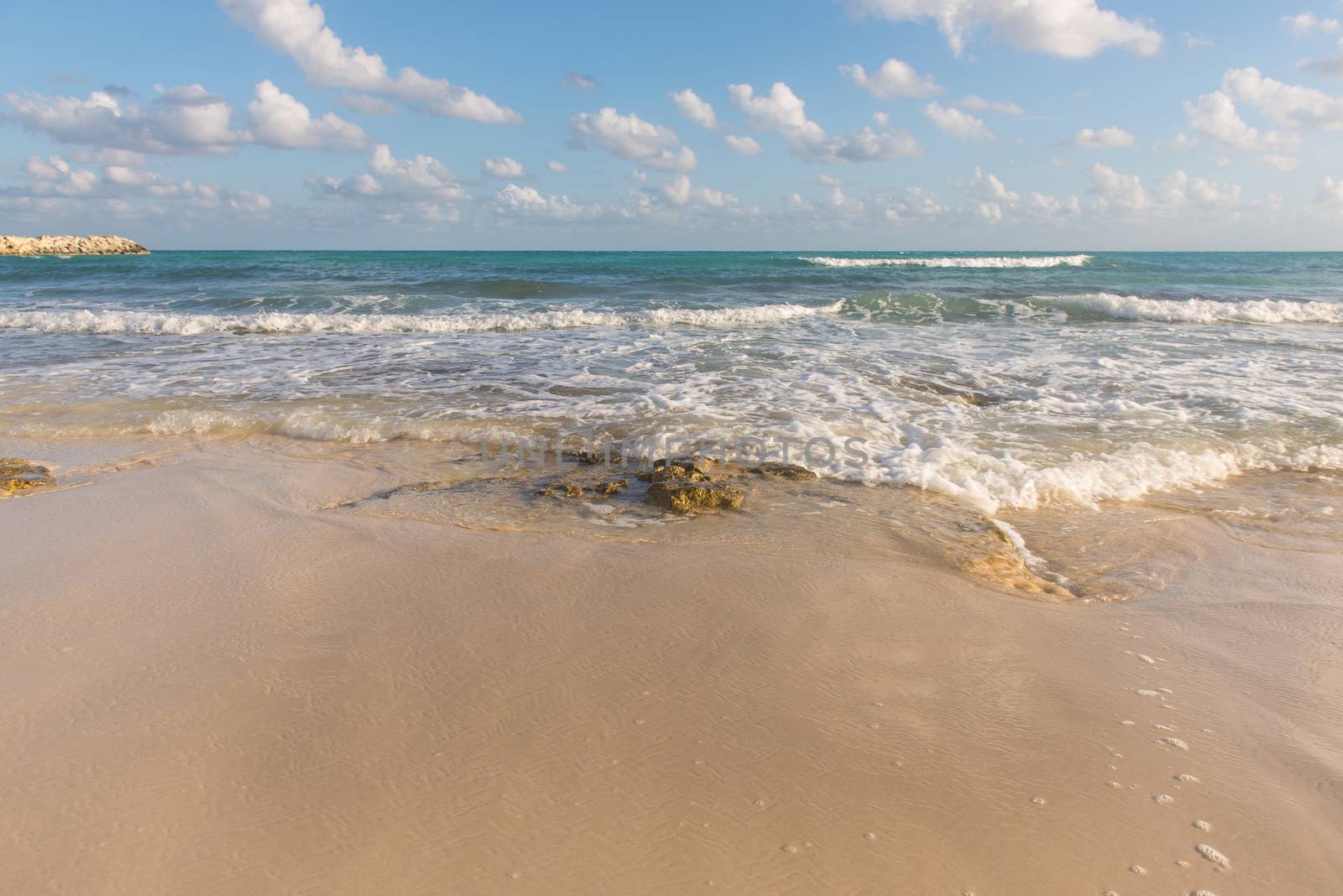 Granite rocks lay in  sand on a Cancun beach at sunset, Mexico.