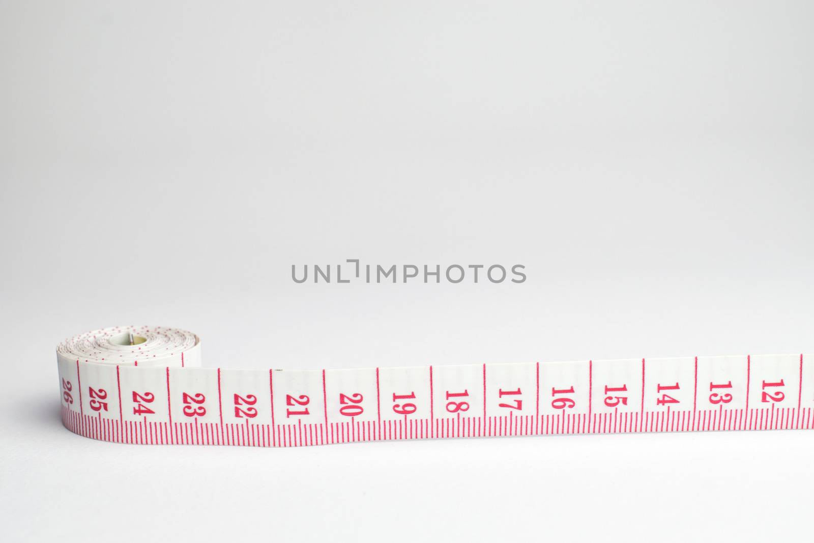 An image of a rolled tape measure on a white background