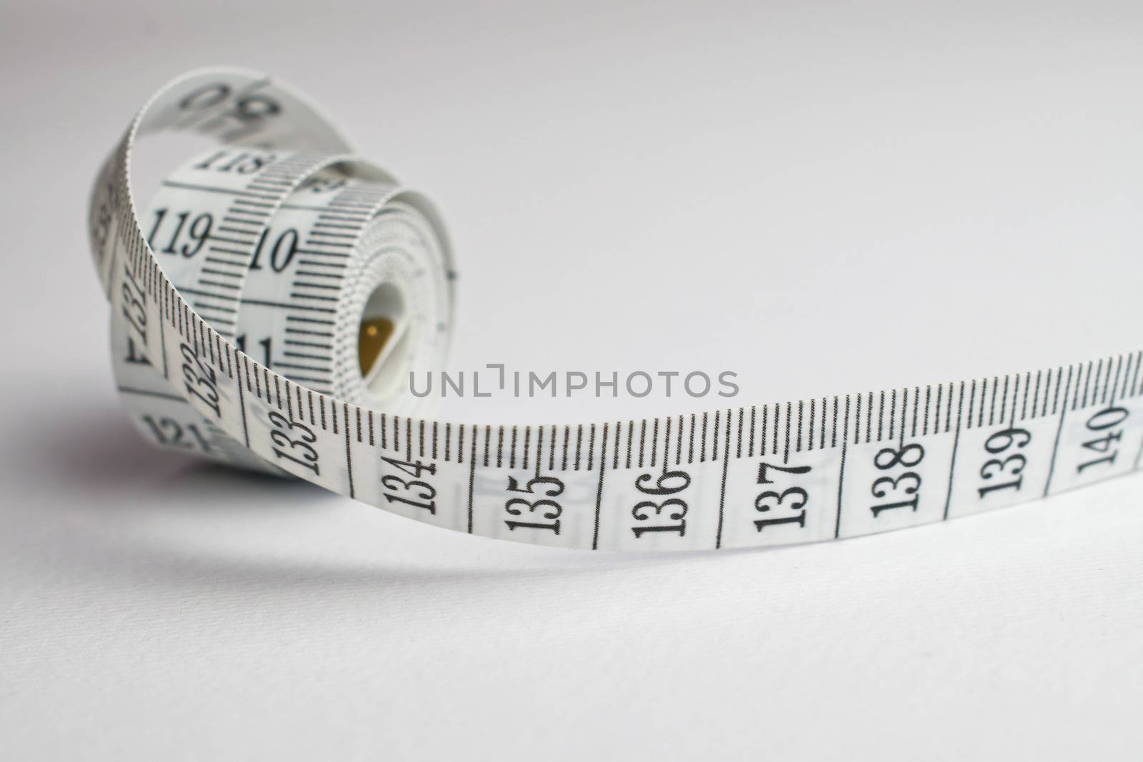 An image of a rolled tape measure on a white background