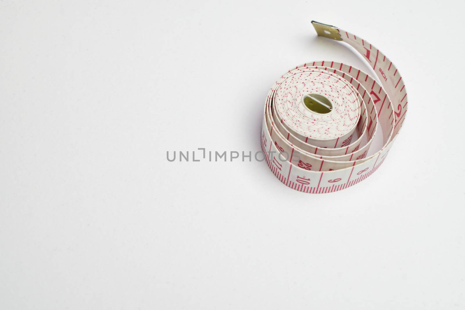 An image of a rolled tape measure on a white background