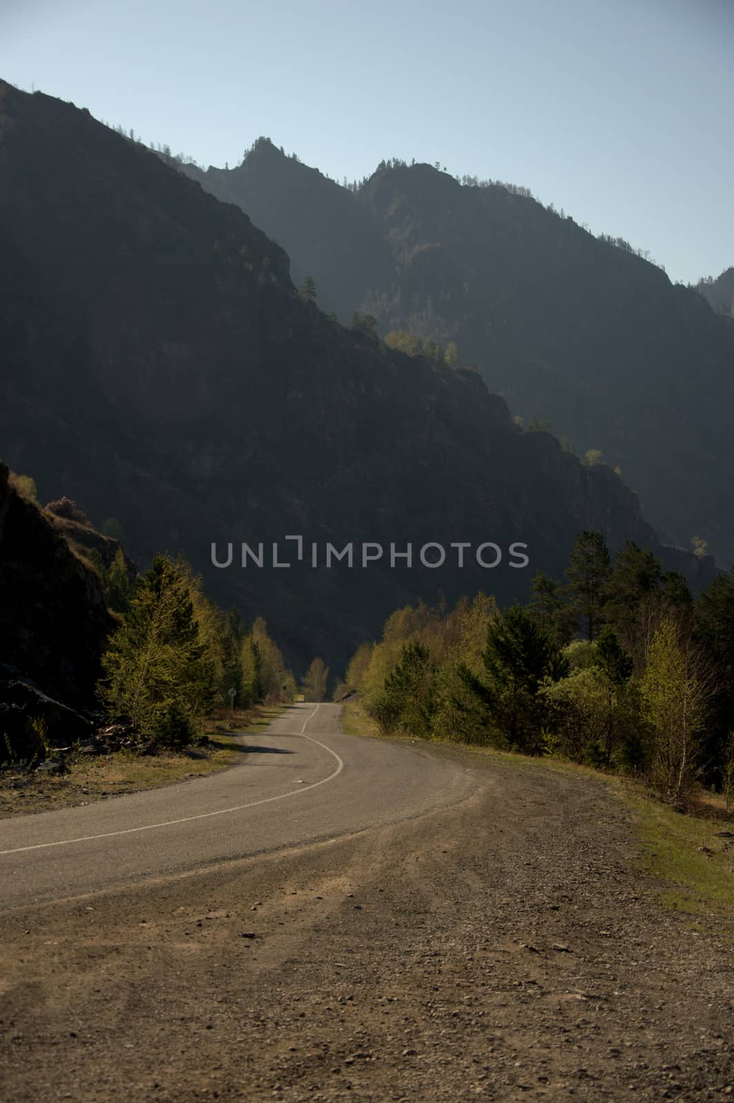 A winding dirt road winding at the foot of the high mountains. Altai, Siberia, Russia.