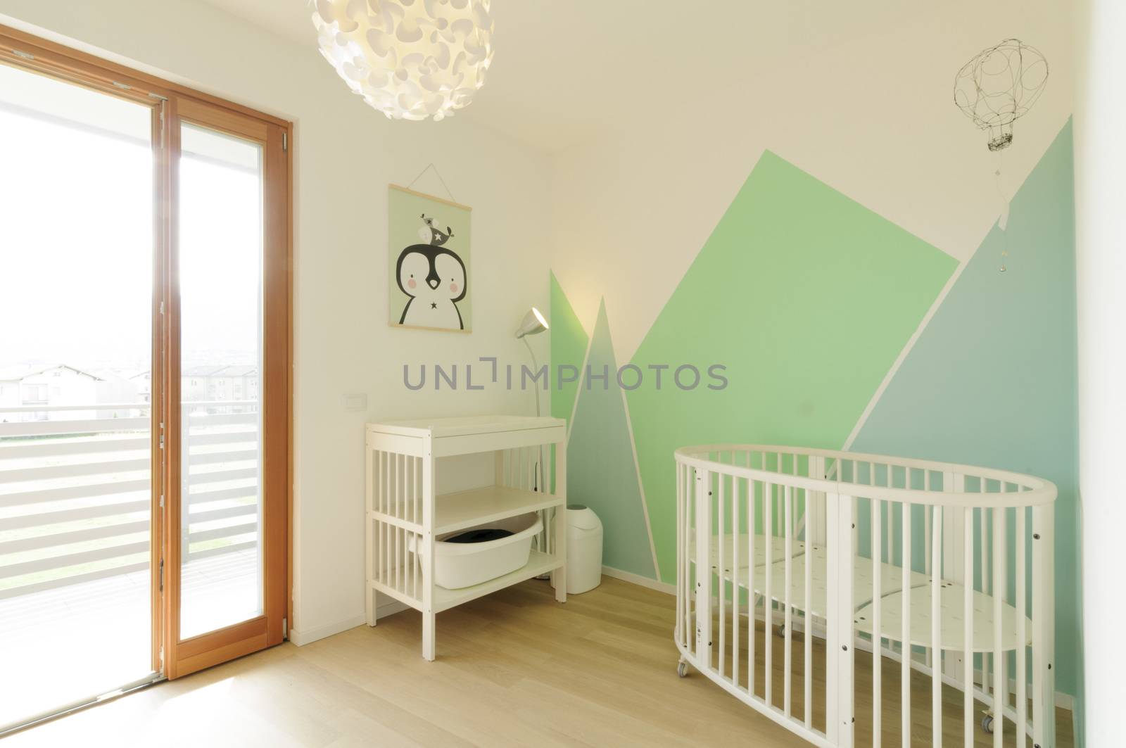 Home interior: bright Scandinavian style nursery with wooden floor and walls painted with geometric shapes in pastel colors