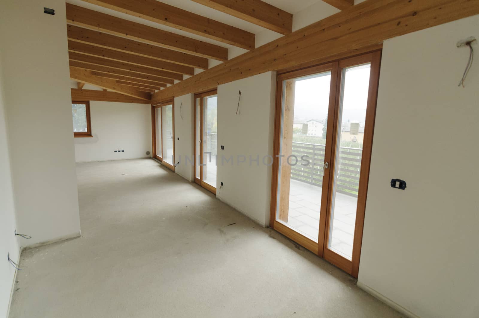 Building site or home renovation in progress: empty open space with large windows and exposed wooden beams