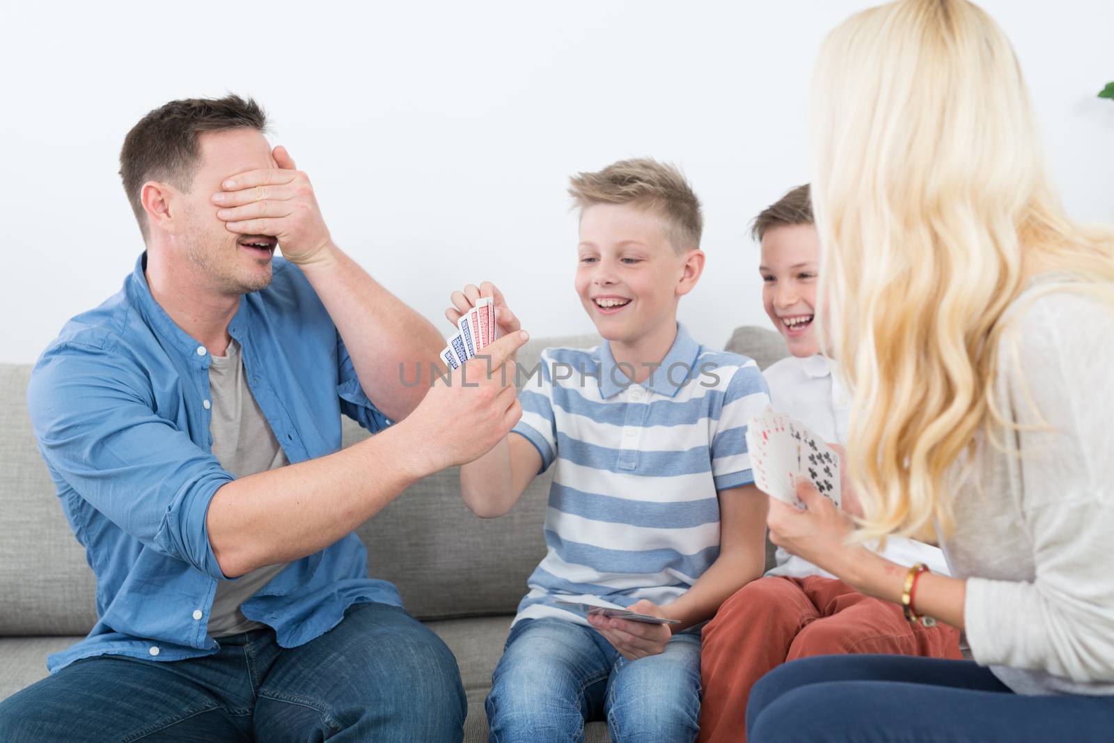 Happy young family playing card game at home. by kasto