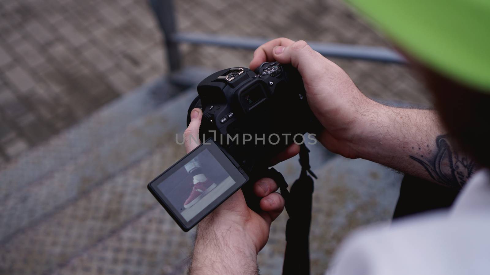 Young man photographer holds camera. Photographer concept. Swivel camera screen.