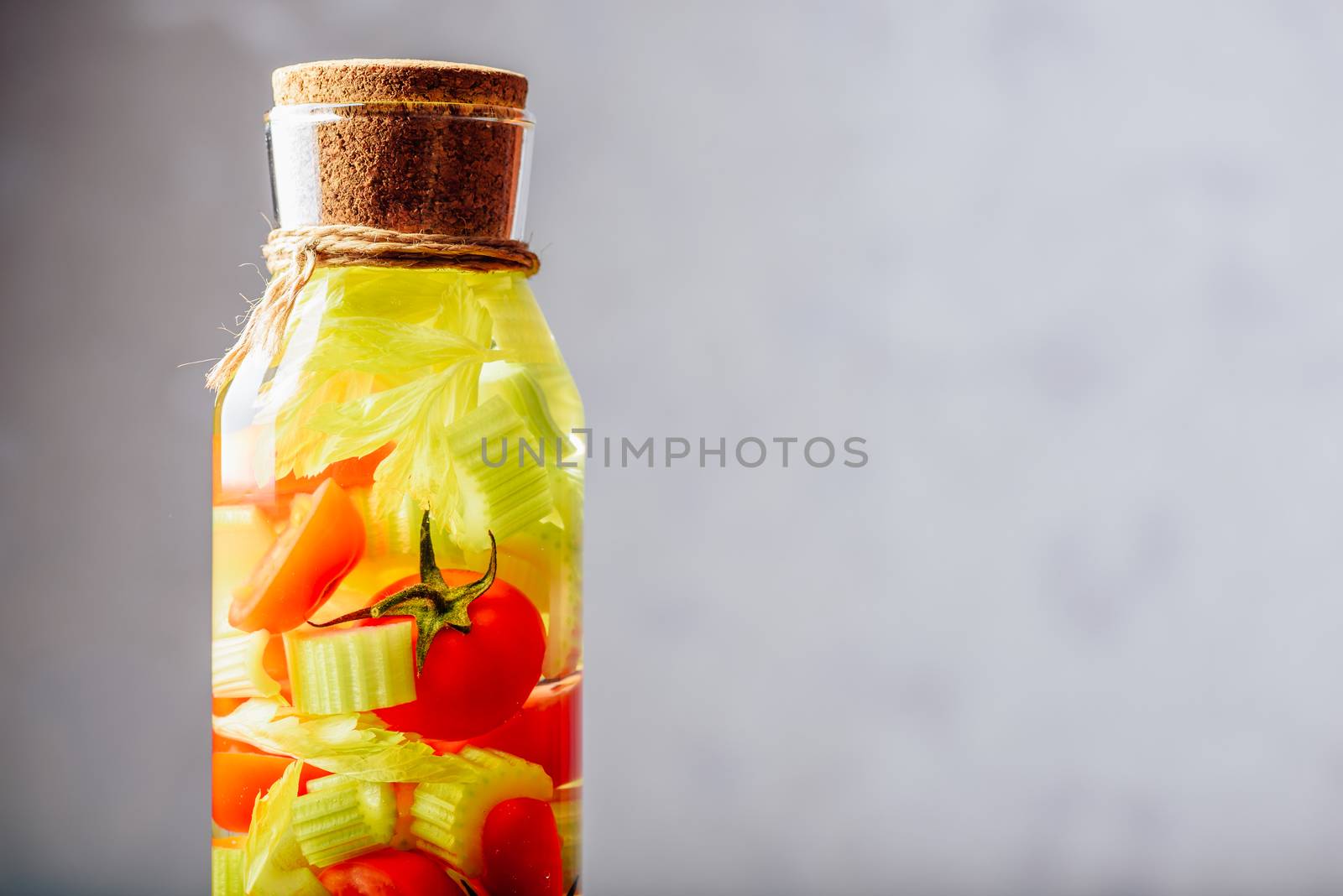 Part of Bottle with Water Infused with Cherry Tomato and Celery Stems. Copy Space on the Right.