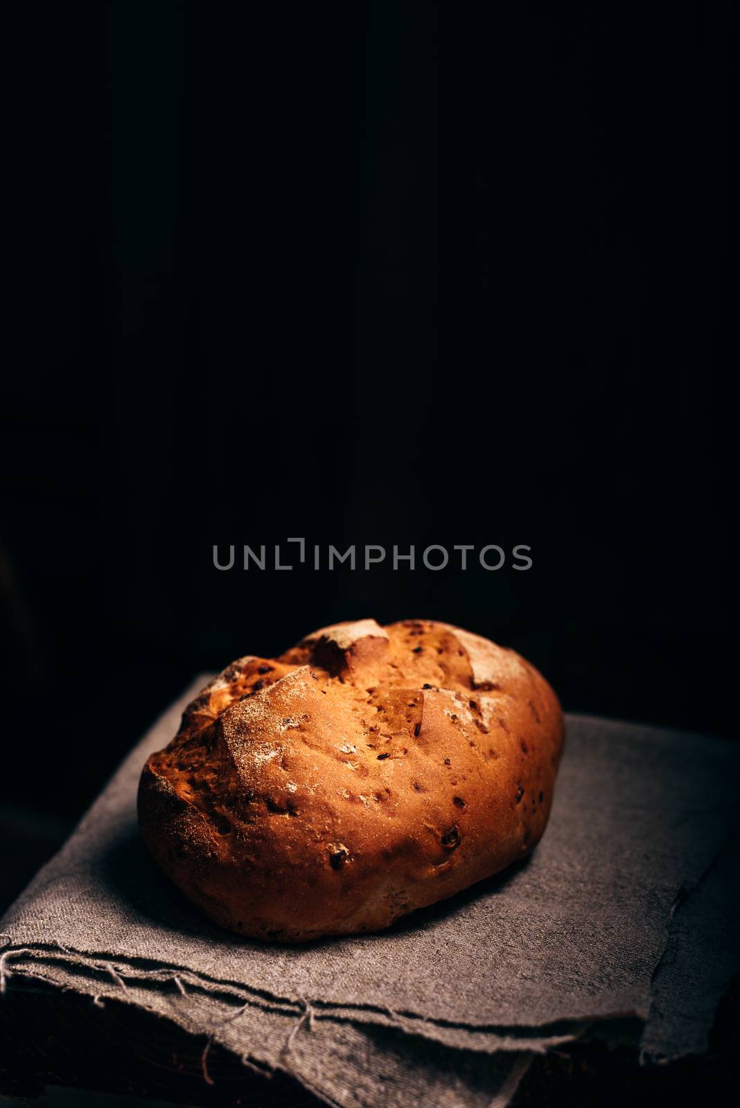 Loaf of Bread on Grey Cloth. Dark Background and Copy Space on the Top.