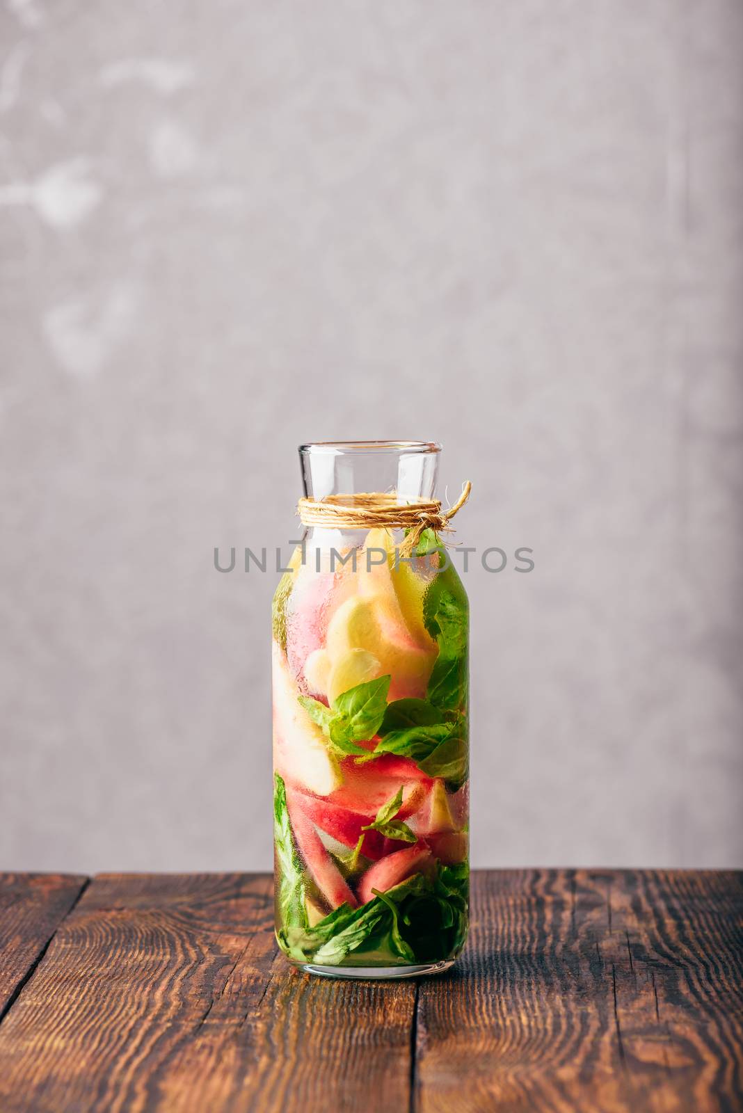Bottle of Infused Water with Sliced Peach and Basil Leaves. Vertical Orientation.