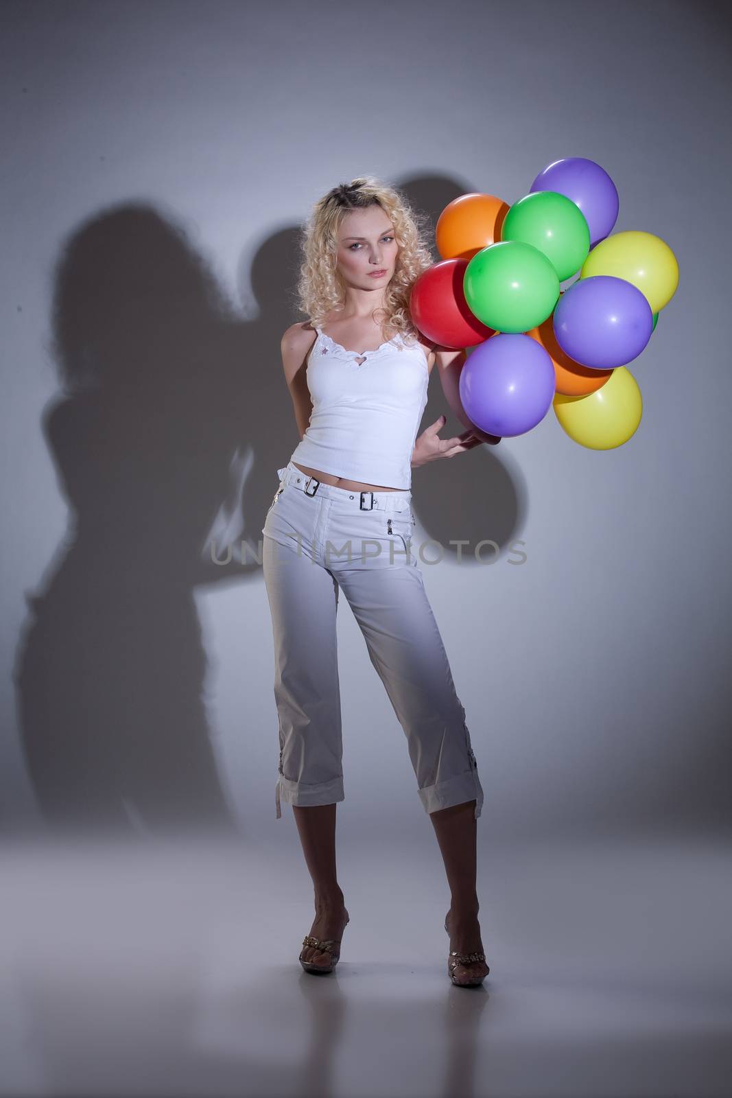 Young blonde beautiful woman in fashionable clothing with coloured balloons