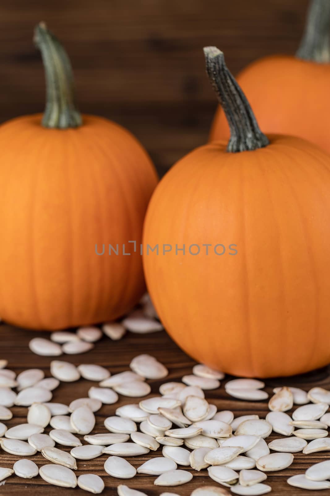 Fresh orange pumpkins and pimpkin seeds close-up on wooden background