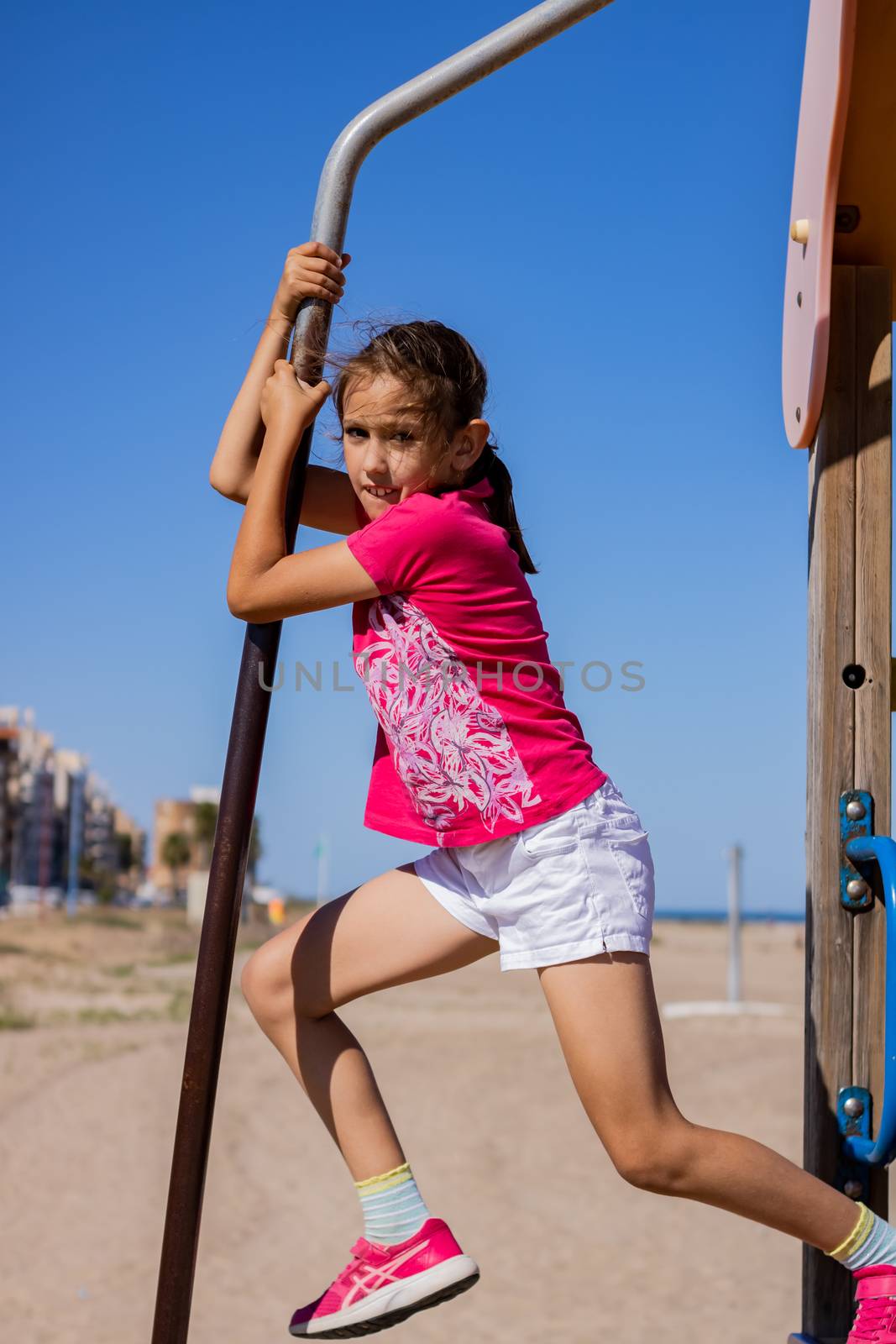 Little girl playing in a playground on the beach