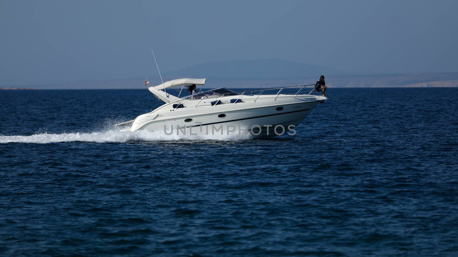 Small launch boat with people, blue sea and sky