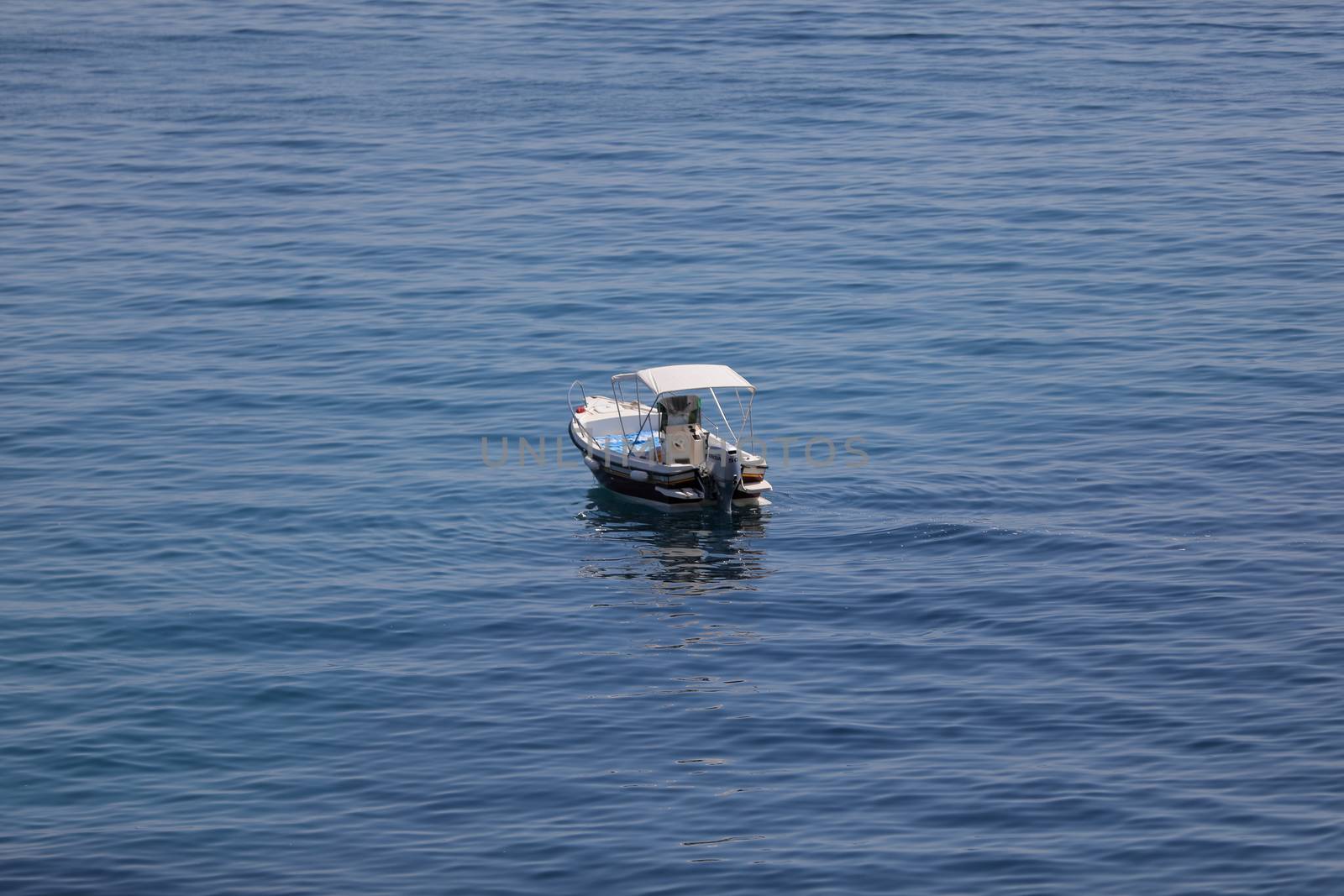 Small launch boat with people, blue sea and sky