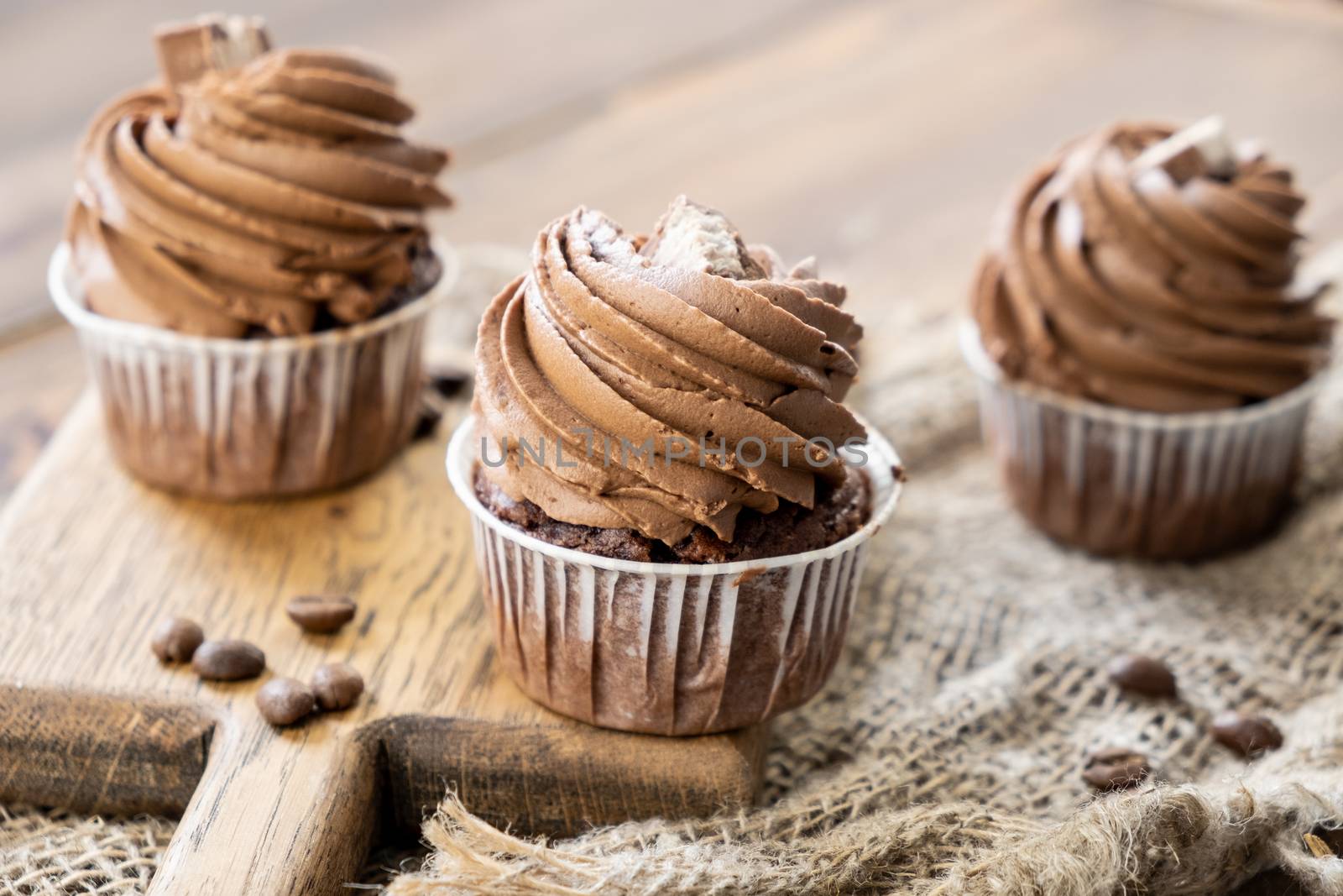 brown cupcakes with cocoa cream, cinnamon and coffee on wooden background by rdv27