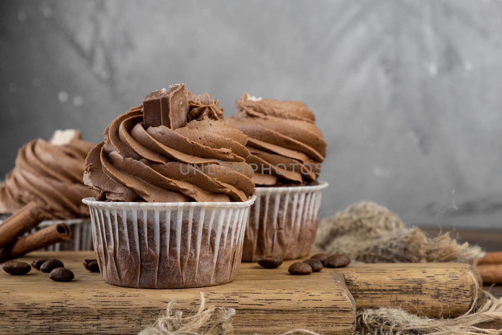 brown cupcakes with cocoa cream, cinnamon and coffee on wooden background by rdv27