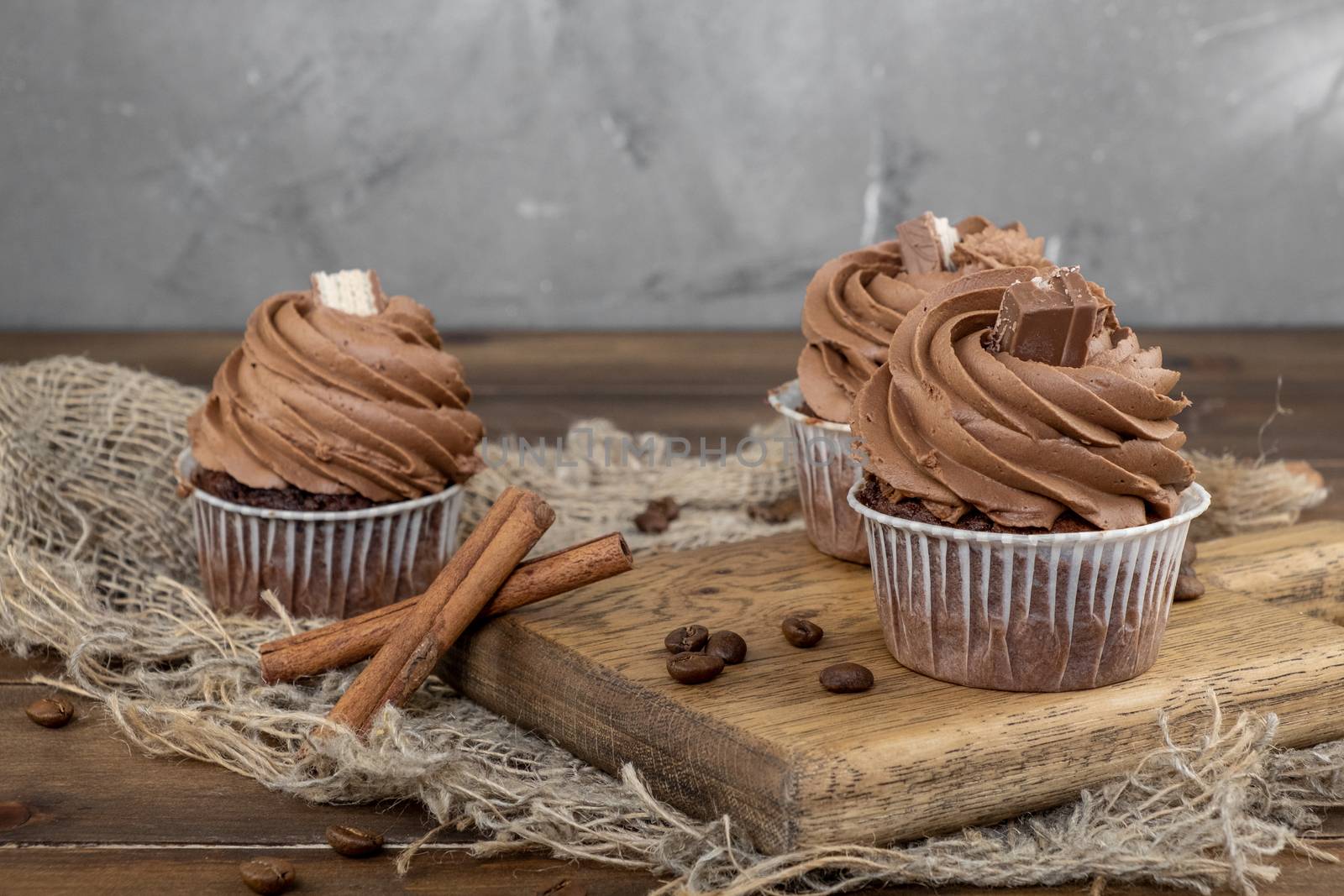 brown cupcakes with cocoa cream, cinnamon and coffee on wooden background by rdv27