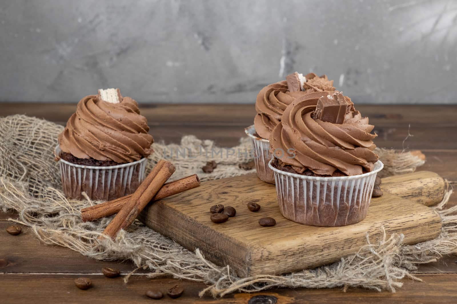 brown cupcakes with cocoa cream, cinnamon and coffee on wooden background by rdv27