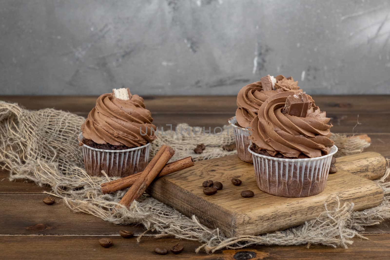 brown cupcakes with cocoa cream, cinnamon and coffee on wooden background by rdv27