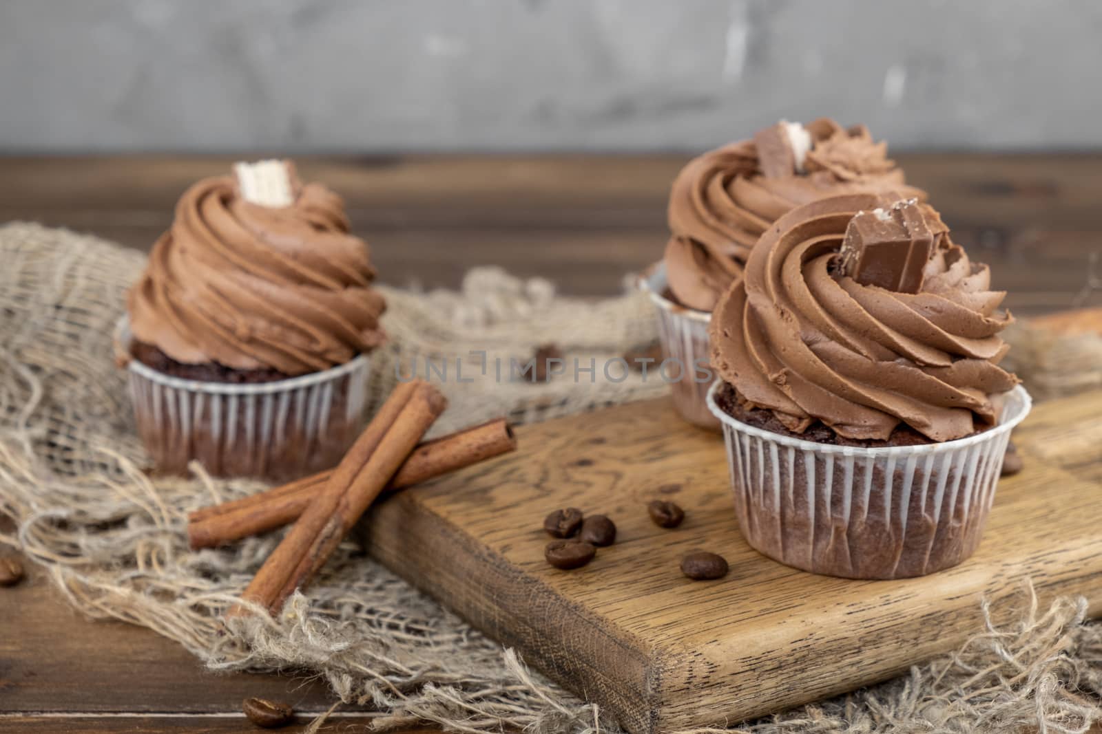 brown cupcakes with cocoa cream, cinnamon and coffee on wooden background by rdv27